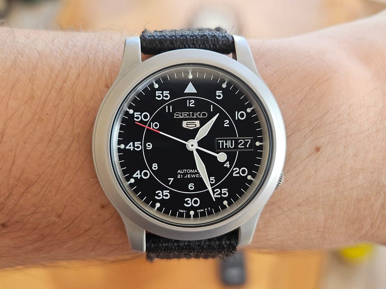 Seiko 5 SNK809 en la muñeca, con esfera negra de estilo militar y correa de tela